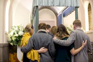 a group of couples holding each other at a funeral