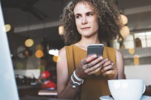 woman using her phone and laptop in a public cafe